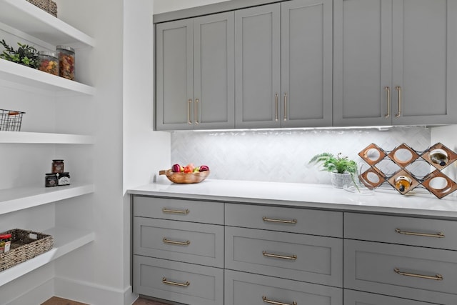 bar featuring backsplash and gray cabinetry