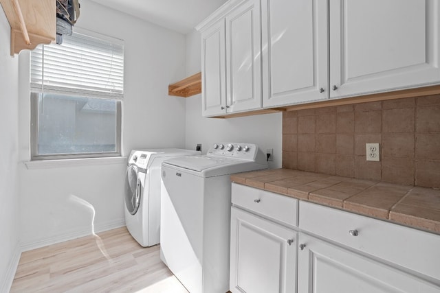 washroom with cabinets, washing machine and dryer, and light hardwood / wood-style flooring