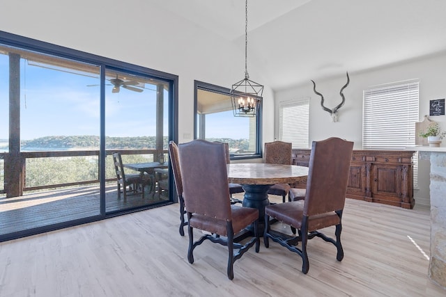 dining area with ceiling fan with notable chandelier, lofted ceiling, and light wood-type flooring