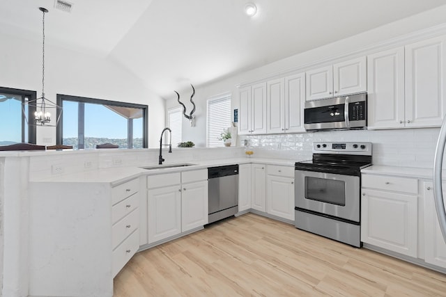 kitchen with pendant lighting, sink, vaulted ceiling, appliances with stainless steel finishes, and white cabinetry