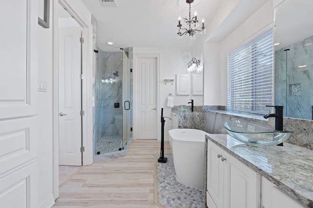 bathroom featuring hardwood / wood-style floors, vanity, a chandelier, and shower with separate bathtub