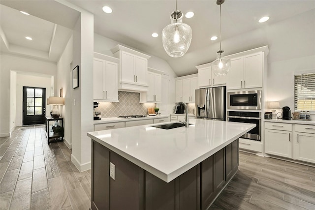 kitchen with appliances with stainless steel finishes, an island with sink, white cabinetry, and sink