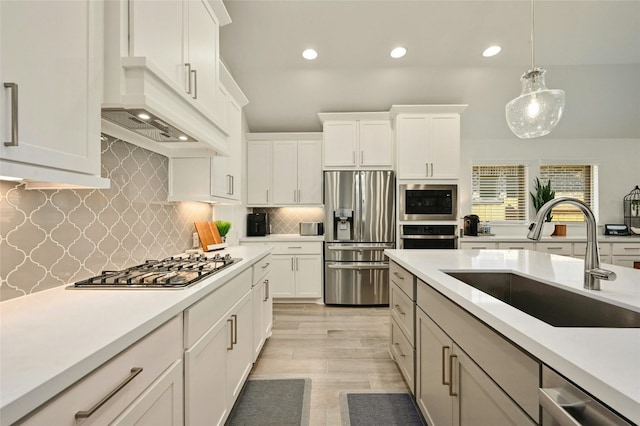 kitchen featuring sink, hanging light fixtures, light wood-type flooring, white cabinetry, and stainless steel appliances