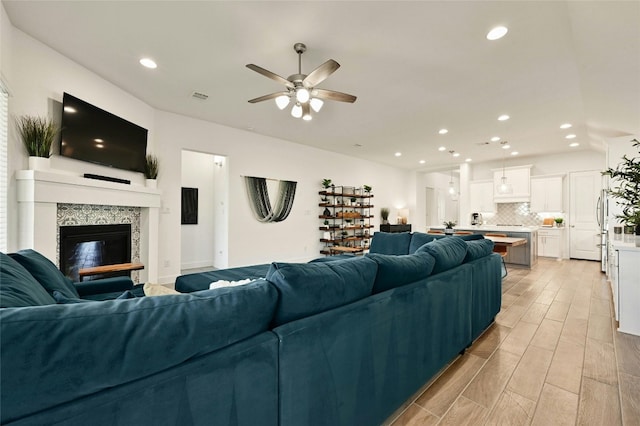 living room with ceiling fan and a premium fireplace