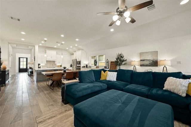 living room with ceiling fan, lofted ceiling, and sink