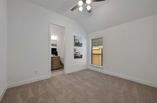 carpeted empty room featuring vaulted ceiling and ceiling fan