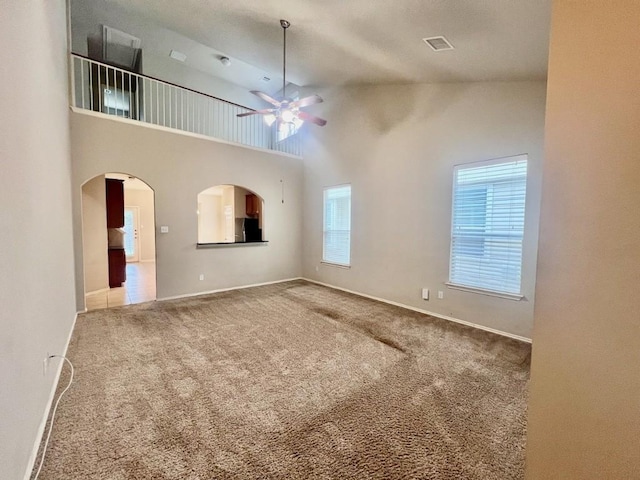 unfurnished living room featuring carpet, ceiling fan, and high vaulted ceiling