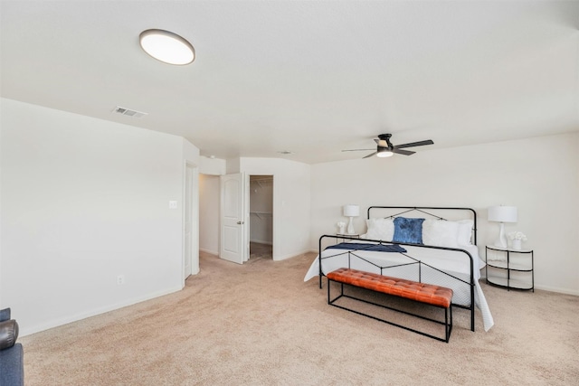 carpeted bedroom with a walk in closet, ceiling fan, and a closet