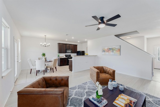 living room featuring ceiling fan with notable chandelier and light wood-type flooring