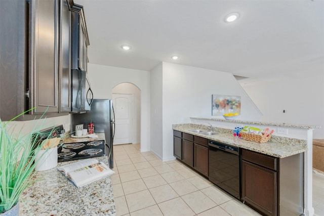 kitchen with dark brown cabinetry, sink, black dishwasher, light stone counters, and light tile patterned floors