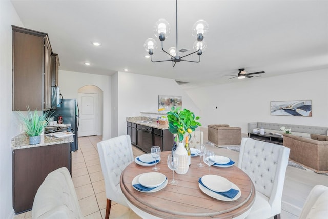 tiled dining room featuring ceiling fan with notable chandelier and sink