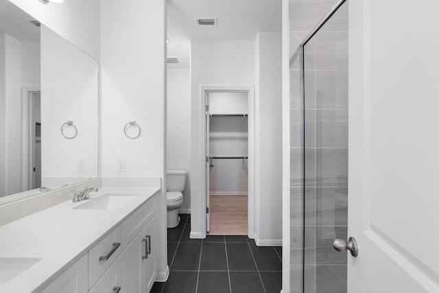 bathroom with vanity, tiled shower, tile patterned floors, and toilet