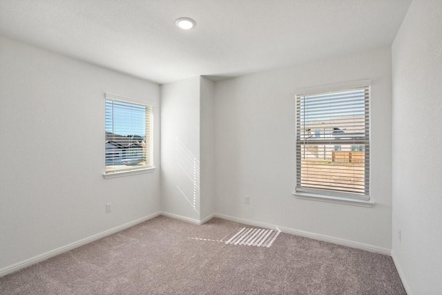 carpeted spare room featuring plenty of natural light