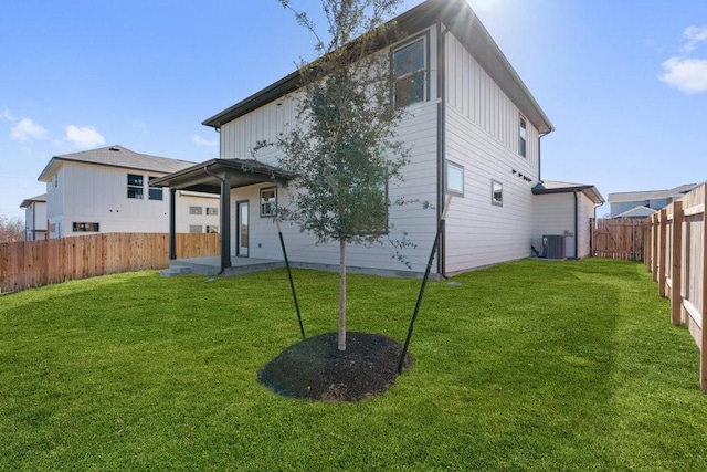 back of property featuring central AC unit and a yard