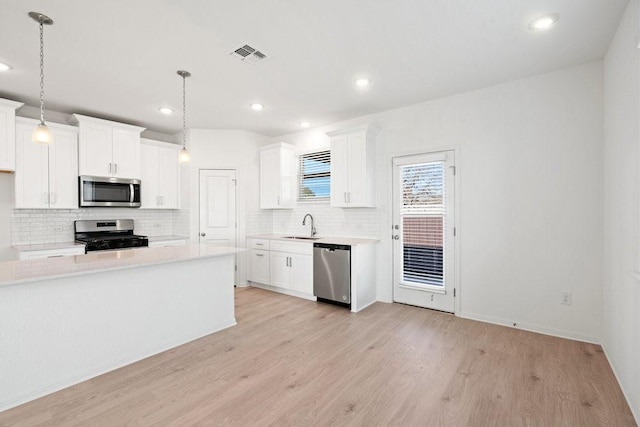 kitchen featuring white cabinetry, hanging light fixtures, and stainless steel appliances