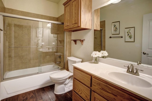 full bathroom featuring hardwood / wood-style floors, vanity, toilet, and enclosed tub / shower combo