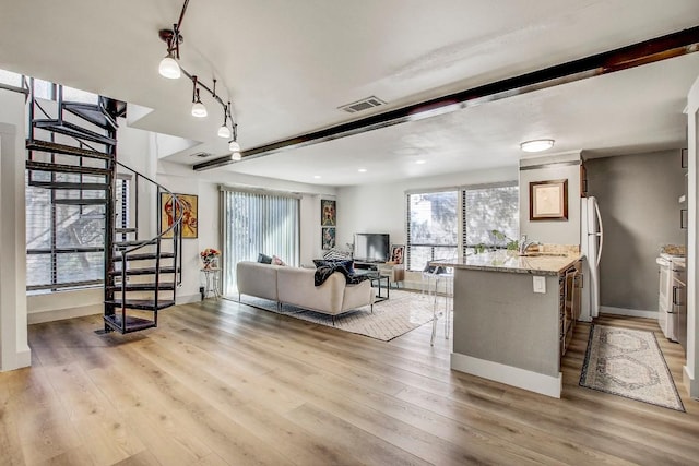 living room with beam ceiling, light wood-type flooring, and sink