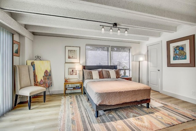 bedroom featuring beamed ceiling and wood-type flooring