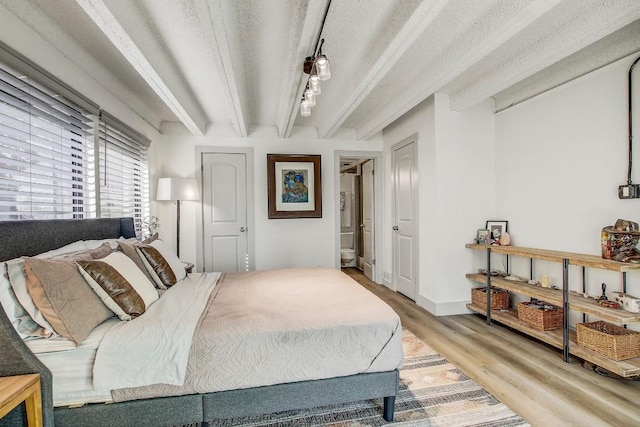 bedroom featuring beam ceiling, light hardwood / wood-style flooring, and a textured ceiling