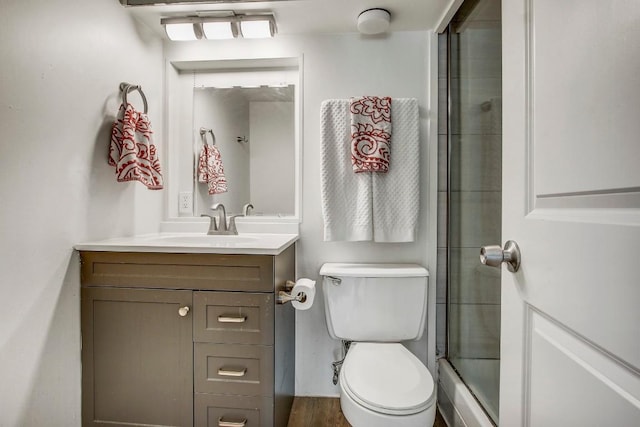 bathroom featuring hardwood / wood-style floors, vanity, toilet, and a shower with door