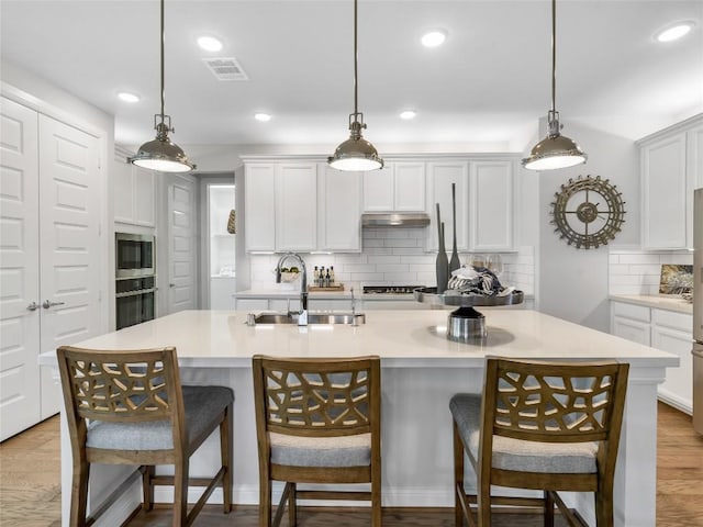 kitchen featuring pendant lighting, sink, appliances with stainless steel finishes, and an island with sink