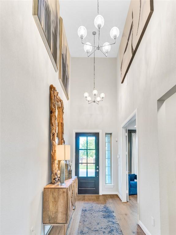 foyer featuring a chandelier, light wood-type flooring, and a towering ceiling