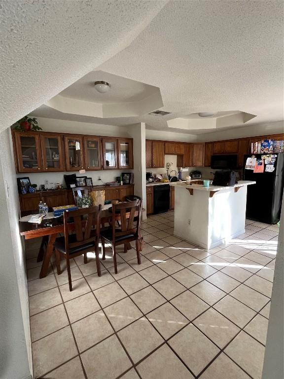 tiled dining area with a raised ceiling and a textured ceiling