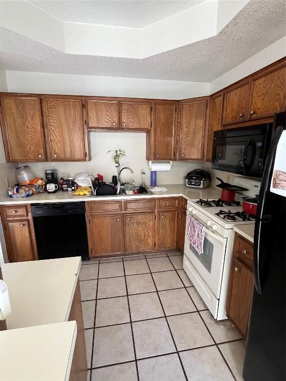 kitchen featuring black appliances, sink, light tile patterned floors, and a textured ceiling