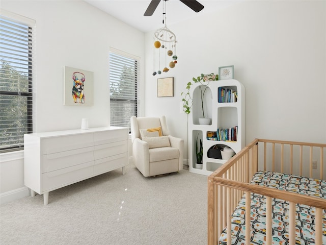 bedroom with a crib, carpet floors, and ceiling fan