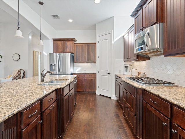 kitchen featuring sink, hanging light fixtures, dark wood-type flooring, stainless steel appliances, and light stone counters