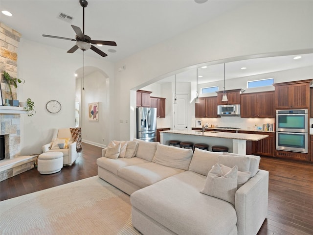 living room featuring a fireplace, ceiling fan, dark wood-type flooring, and sink