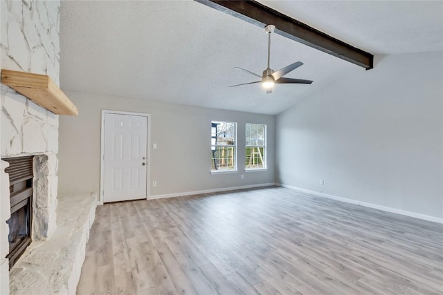 unfurnished living room with light hardwood / wood-style flooring, vaulted ceiling with beams, ceiling fan, a textured ceiling, and a fireplace