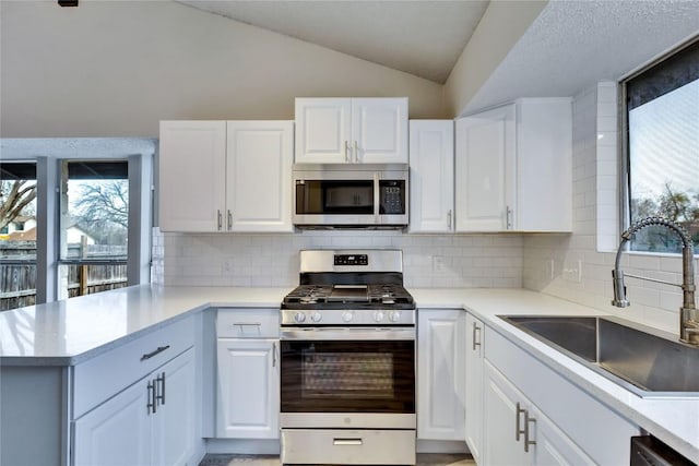 kitchen featuring lofted ceiling, backsplash, white cabinets, sink, and stainless steel appliances