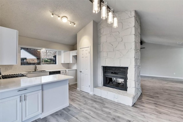 kitchen with white cabinetry, sink, pendant lighting, and a textured ceiling