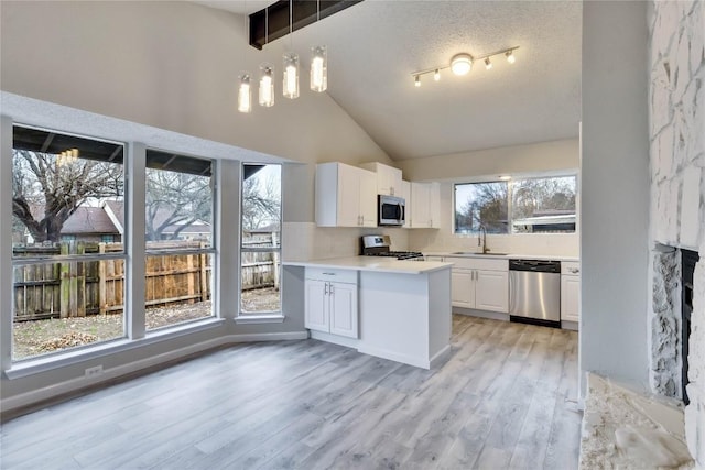 kitchen with white cabinets, pendant lighting, sink, and appliances with stainless steel finishes