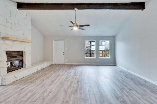 unfurnished living room with ceiling fan, light hardwood / wood-style floors, a stone fireplace, and vaulted ceiling