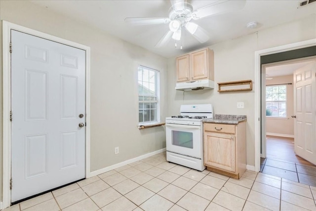 kitchen featuring white gas range, light tile patterned floors, ceiling fan, and light brown cabinets