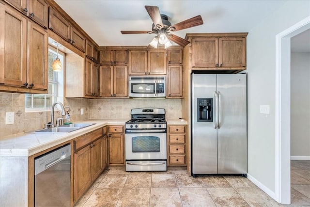 kitchen featuring sink, light tile patterned floors, appliances with stainless steel finishes, ceiling fan, and decorative backsplash