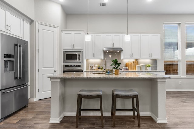 kitchen with white cabinetry, a kitchen island with sink, hanging light fixtures, and stainless steel appliances