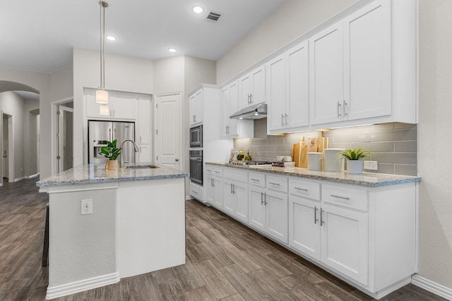 kitchen with appliances with stainless steel finishes, sink, pendant lighting, white cabinets, and an island with sink