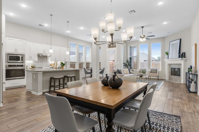 dining area featuring ceiling fan with notable chandelier and sink