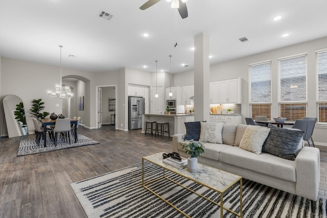 living room featuring dark hardwood / wood-style flooring and ceiling fan with notable chandelier