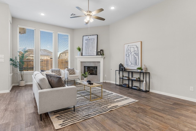 living room with hardwood / wood-style floors, ceiling fan, and a tiled fireplace