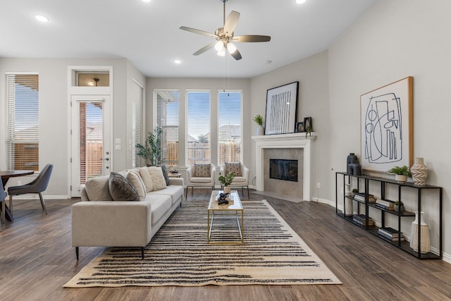 living room with ceiling fan, a fireplace, and dark wood-type flooring