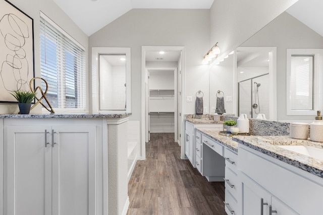 bathroom with wood-type flooring, vanity, vaulted ceiling, and an enclosed shower