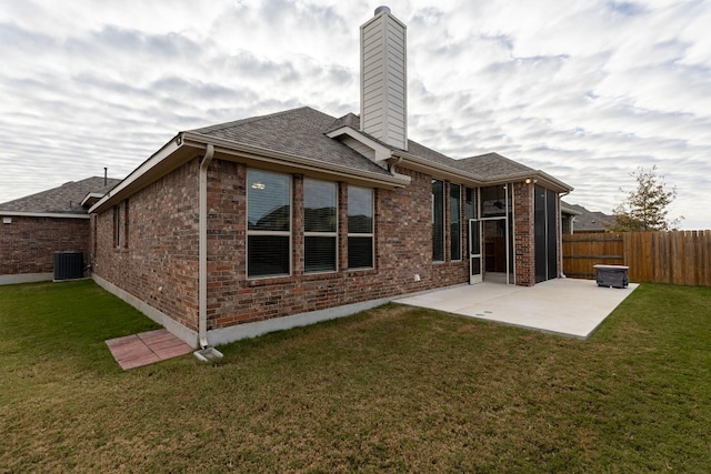 rear view of property with a patio, central air condition unit, and a lawn