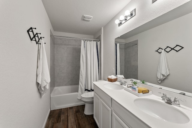 full bathroom with hardwood / wood-style floors, vanity, toilet, shower / bath combo, and a textured ceiling