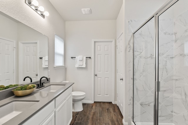 bathroom featuring vanity, hardwood / wood-style flooring, a shower with shower door, and toilet