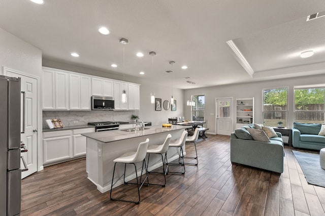 kitchen with white cabinetry, an island with sink, appliances with stainless steel finishes, and a kitchen breakfast bar