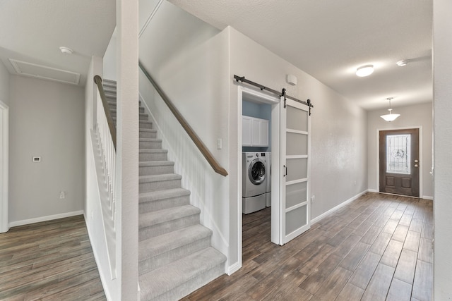 entryway featuring a barn door, washer / dryer, dark wood-type flooring, and a textured ceiling